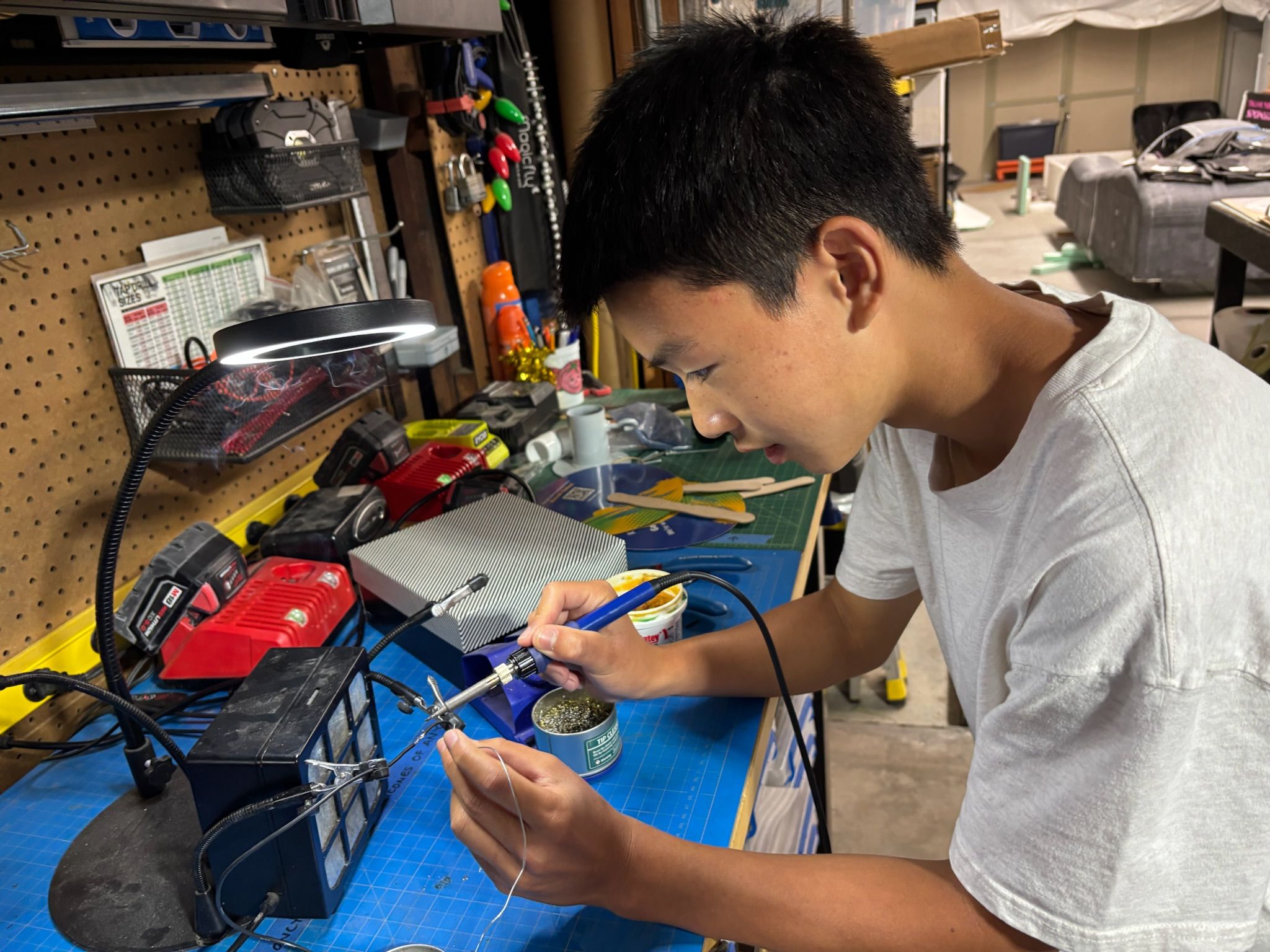 Student soldering the electronics harness for the first prototype on a workbench 5